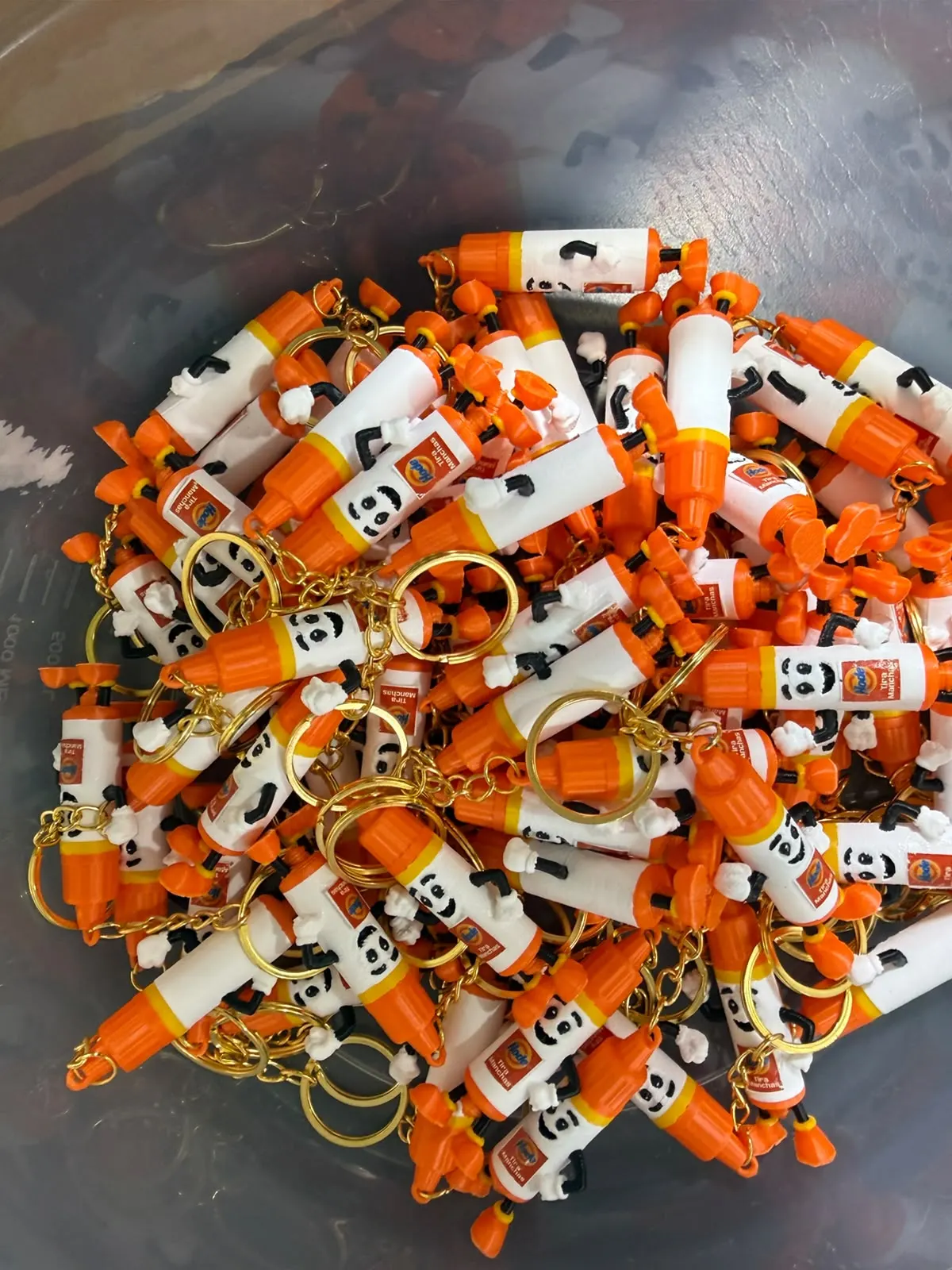 Lote de chaveiros laranja e branco reunido após a produção